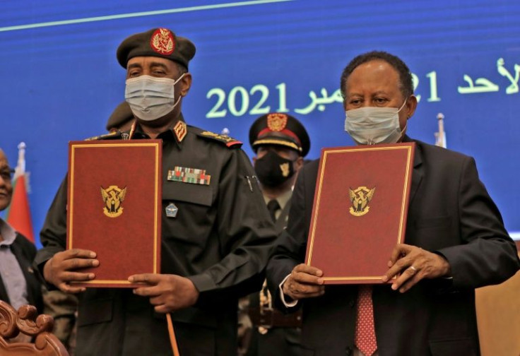 Sudan's top general Abdel Fattah al-Burhan (L) and Prime Minister Abdalla Hamdok lift documents during a deal-signing ceremony on November 21