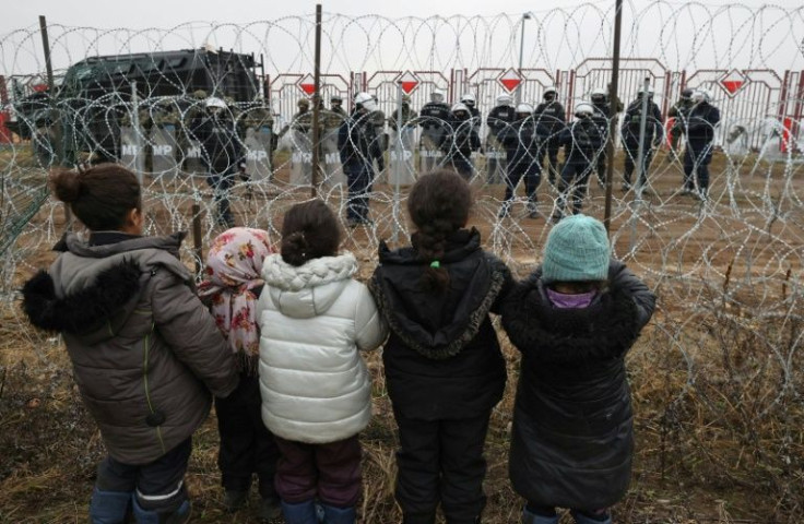 Migrants in Belarus look across the border into Poland where security forces are positioned