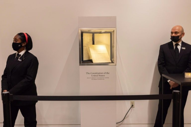 Security guards stand next to the first printing of the United States Constitution during an auction at Sotheby's auction house in New York