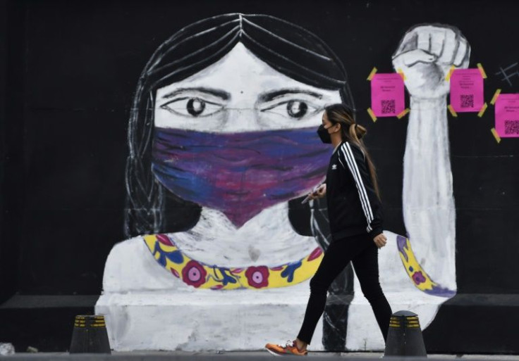 A woman walks in front of graffiti before a demonstration to mark the International Day for the Elimination of Violence against Women in Mexico City
