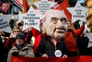 An activist from the Extinction Rebellion (XR) climate change group, wearing a mask depicting Amazon founder Jeff Bezos, takes part in a protest outside the company's headquarters in London on November 26, 2021