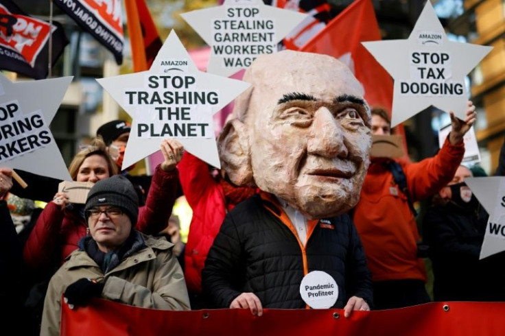 An activist from the Extinction Rebellion (XR) climate change group, wearing a mask depicting Amazon founder Jeff Bezos, takes part in a protest outside the company's headquarters in London on November 26, 2021