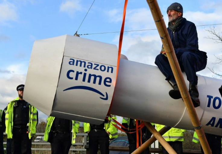 A protester sits astride a wooden model of a rocket during action outside an Amazon distribution centre in Tilbury, east of London
