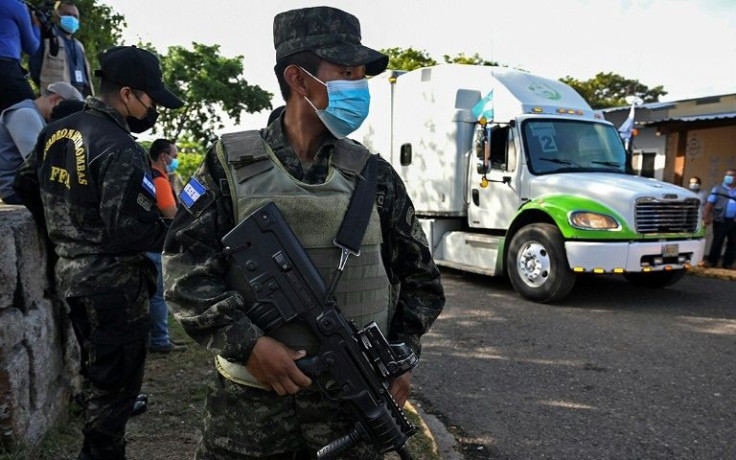 Soldiers stand guard as trucks distributing electoral material leave the National Institute of Professional Formation in Tegucigalpa on November 23
