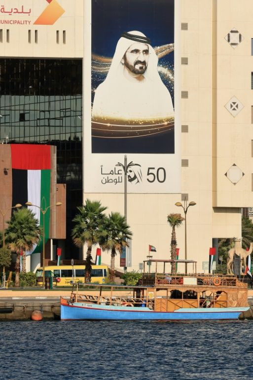 An Emirati flag and a banner bearing the portrait of Dubai's ruler Sheikh Mohammed bin Rashid Al-Maktoum hang on the side of a building in the Gulf emirate
