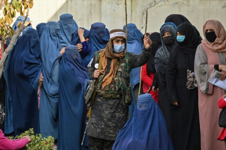A Taliban fighter keeps order as women wait in a queue during a World Food Programme distribution in Kabul