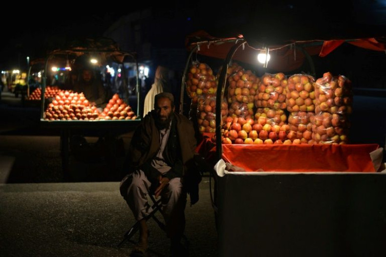 A vendor selling apples waits for customers along a street on November 30, 2021, in Kandahar, Afghanistan, where food prices are rising