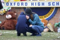 People embrace as they visit a makeshift memorial outside of Oxford High School in Oxford, Michigan, where a 15-year-old killed four fellow students and wounded seven other people in a shooting Tuesday.