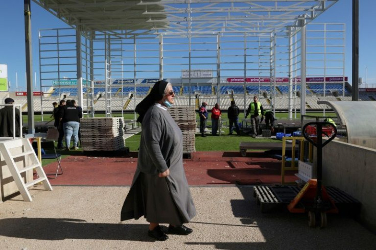 A nun passes workers preparing the stage at Nicosia's GSP football stadium, where Pope Francis is scheduled to conduct a mass before thousands of faithful in Cyprus