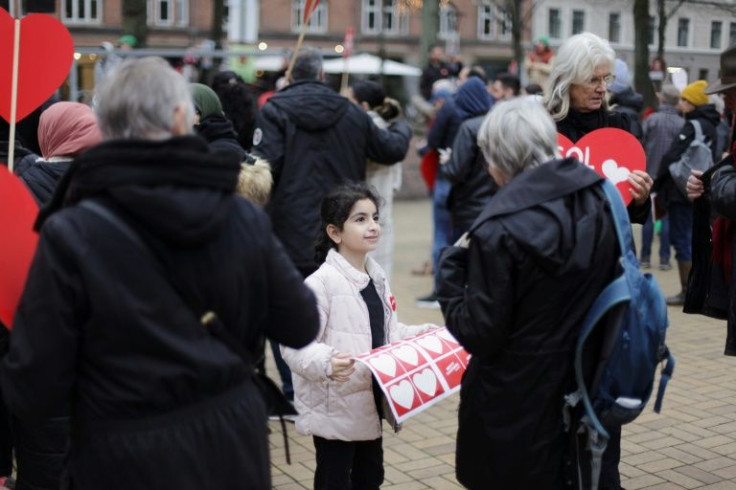 Rawan, 10, daughter of Syrian refugee Bilal Alkale, distributes stickers in support of Syrian families whose lives are on pause in Denmark