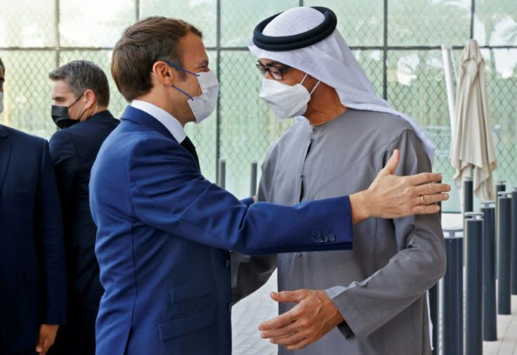 French President Emmanuel Macron (L) is greeted by Abu Dhabi's Crown Prince Mohammed bin Zayed al-Nahyan at the Dubai Expo on the first day of his Gulf tour