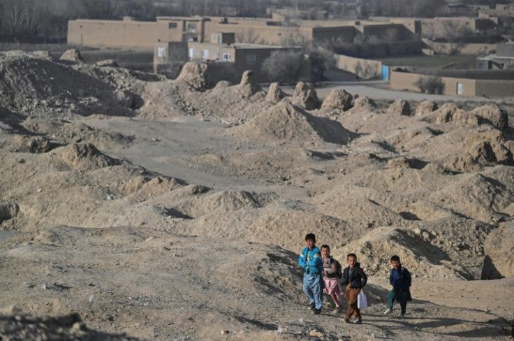 Children walk amid the ruins of destroyed houses in Arzo