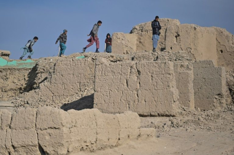 Children walk over the ruins of destroyed houses in Arzo
