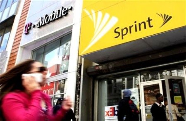 A woman using a cell phone walks past T-Mobile and Sprint stores