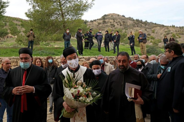 Turkish security forces (back) keep watch as Lebanon's Maronite Patriarch Bechara al-Rahi (C, with flowers) arrives at the small Agia Marina Maronite church in the self-proclaimed Turkish Republic of Northern Cyprus