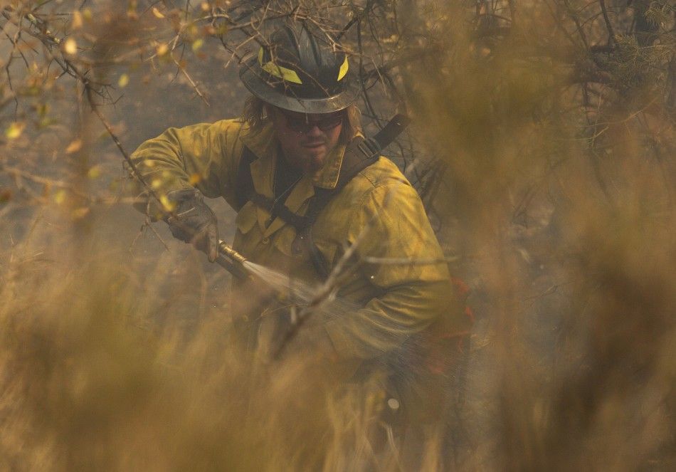 A wildland firefighter extinguishes a hot spot on the eastern edge of the Wallow Wildfire outside Alpine, Arizona