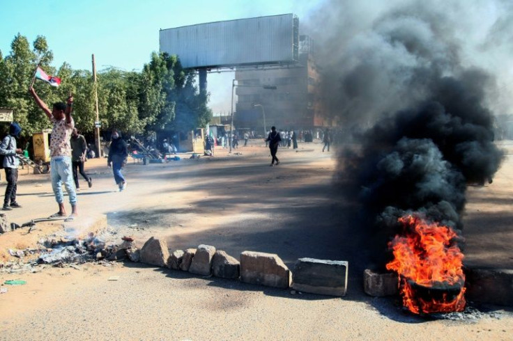Sudanese demonstrators block a road with bricks and burning tyres during a rally in the capital Khartoum, on December 6, 2021, to protest a deal that saw the prime minister reinstated after his ouster in a military coup in October