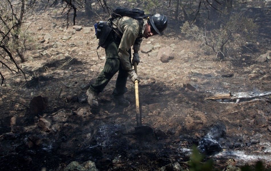 A wildland firefighter works at a hot spot on the eastern edge of the Wallow Wildfire outside Alpine, Arizona
