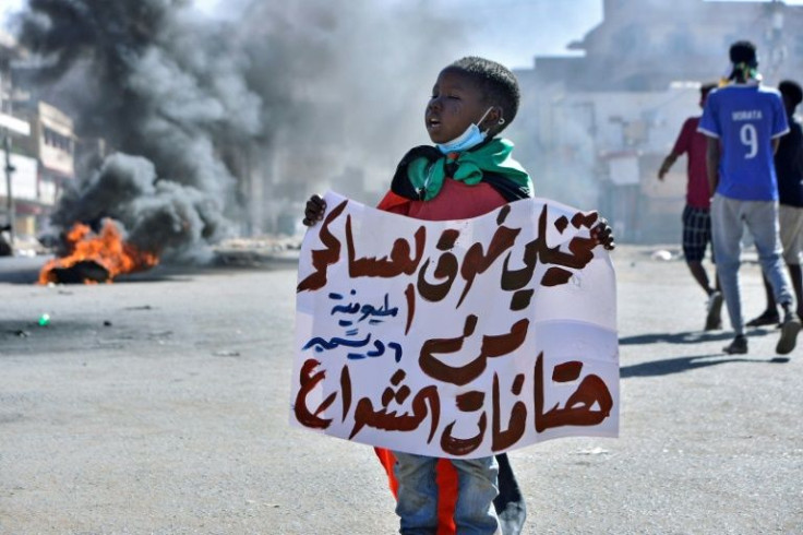A Sudanese boy lifts a banner which reads in Arabic, "Imagine the fear of the military of chants on the streets", during a rally in the capital Khartoum on December 6, 2021, to protest a deal with the military that saw the prime minister reinstated
