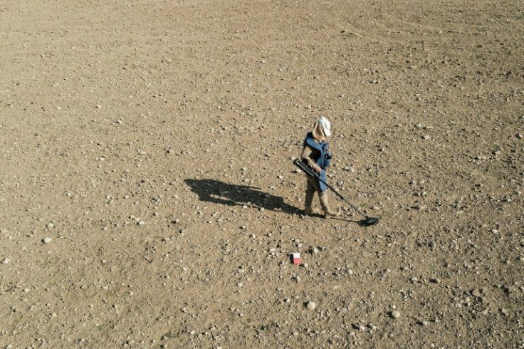 A metal detector searches for unexploded munitions north of Mosul, a former stronghold of the Islamic State (IS) jihadist group, in an area littered with unexploded ordnance