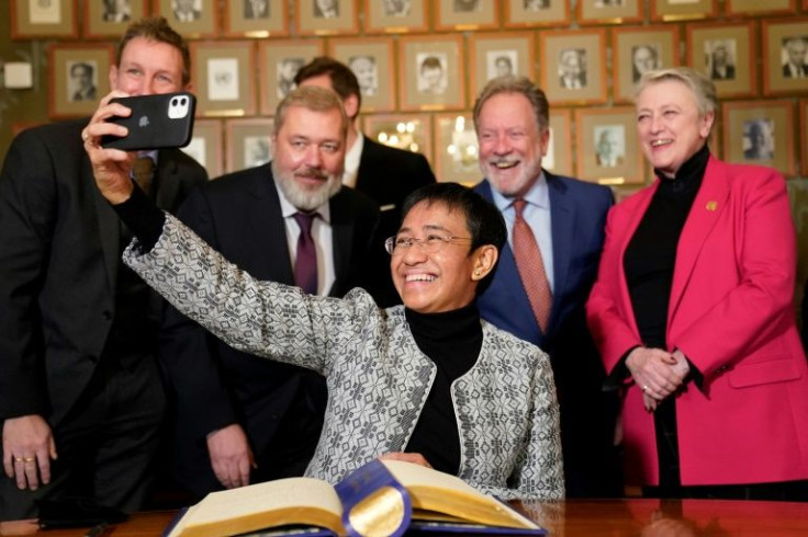 Nobel Peace Prize winner Maria Ressa takes a selfie with fellow winner Dmitry Muratov as both warn of ongoing threats to press freedom