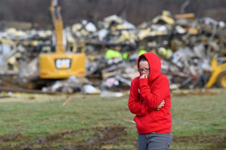 A woman walks away from what is left of the Mayfield Consumer Products Candle Factory as emergency workers comb the rubble after it was destroyed by a tornado in Mayfield, Kentucky, on December 11, 2021