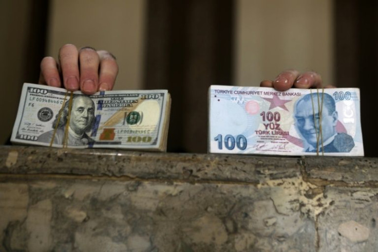 A Syrian man holds stacks of US dollars (L) and Turkish currency, which lost 45 percent of its value against the greenback in 2021