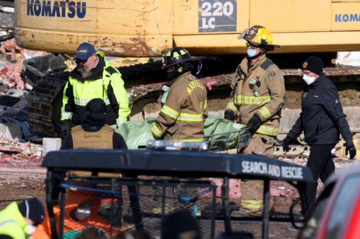 First responders retreieve a body from the rubble at a candle factory destroyed by the storm