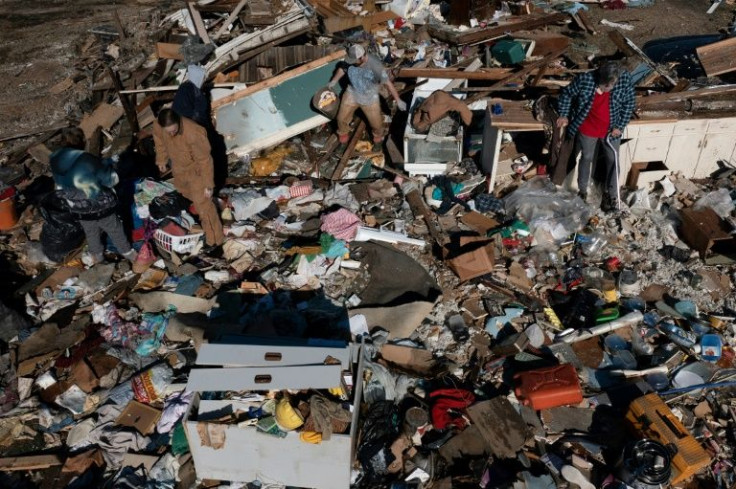 Bogdan Gaicki rests in the rubble of his home as family members help sort through the tornado damage after extreme weather hit the region on December 12, 2021, in Mayfield, Kentucky