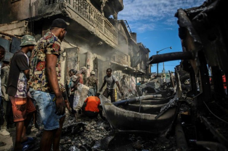 Men pick up aluminum pieces at the site where a tanker truck exploded in Cap-Haitien, Haiti, December 14, 2021