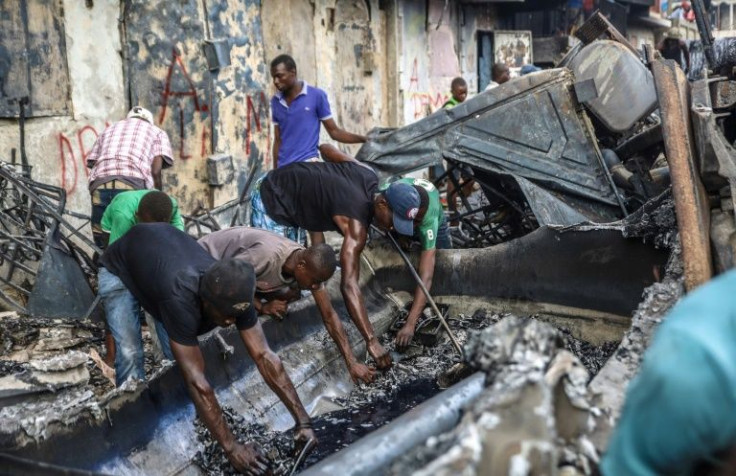 Men strip aluminum pieces at the site where a tanker truck exploded in Cap-Haitien