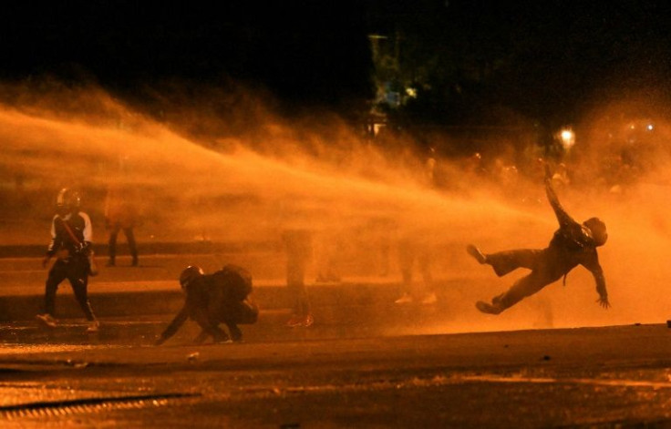 A demonstrator falls as they are hit by water cannon during anti-government protests in Bogota in June 2021