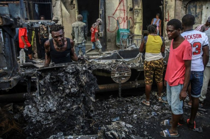 Men pick up debris at the site where the tanker truck exploded in Cap-Haitien, Haiti, December 14, 2021