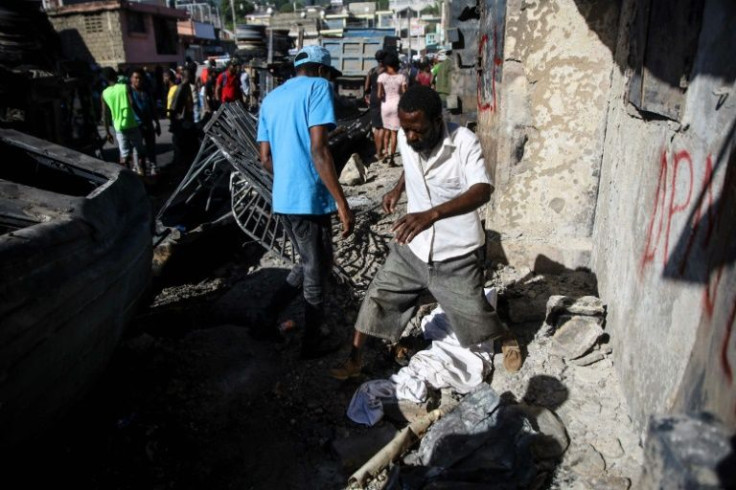 A man steps over a body covered with a sheet in Cap-Haitien, Haiti, on December 15, 2021, the day after a tanker explosion