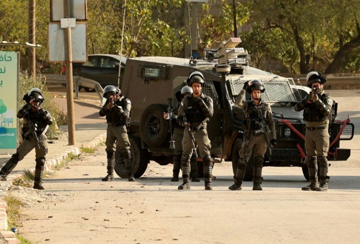 Israeli border guards block the entrance to the Palestinian village of al-Lubban al-Sharqiya, near Nablus city in the occupied West Bank, during a demonstration by settlers on December 14, 2021