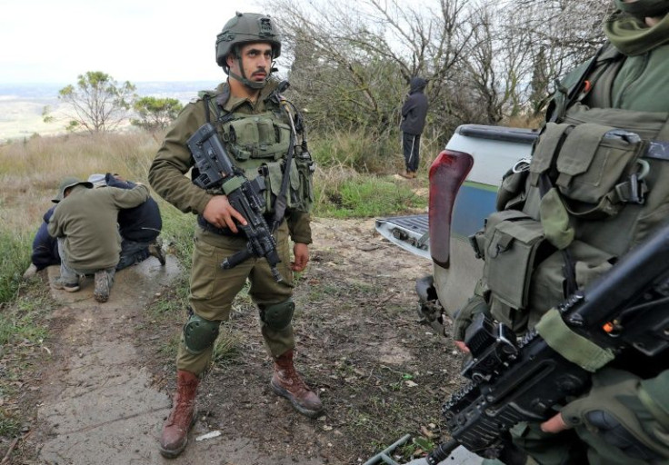 Israeli soldiers stand guard as settlers mourn Yehuda Dimentman, a fellow settler who was shot on December 16, 2021