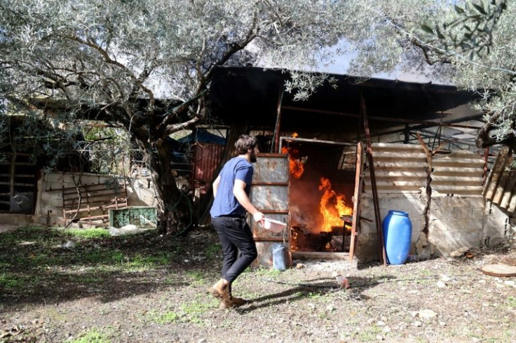 A Palestinian resident of the West Bank village of Burqah tries to extinguish a fire in a hut on December 17, 2021, after reported attacks by Israeli settlers on the village