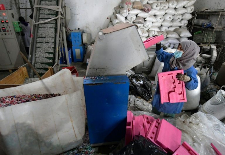 An employee of African Recycling feeds plastic waste into a grinder -- much of the refuse is collected in the streets by informal waste pickers