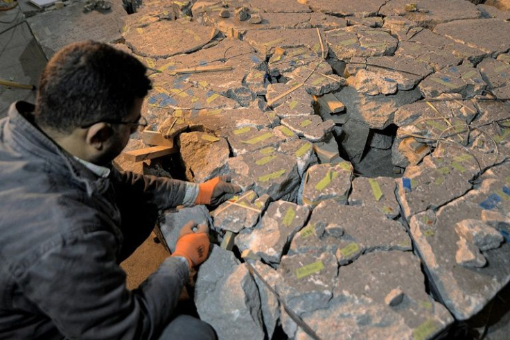 A worker helps reassemble an artefact bearing cuneiform inscriptions at the Mosul museum in northern Iraq