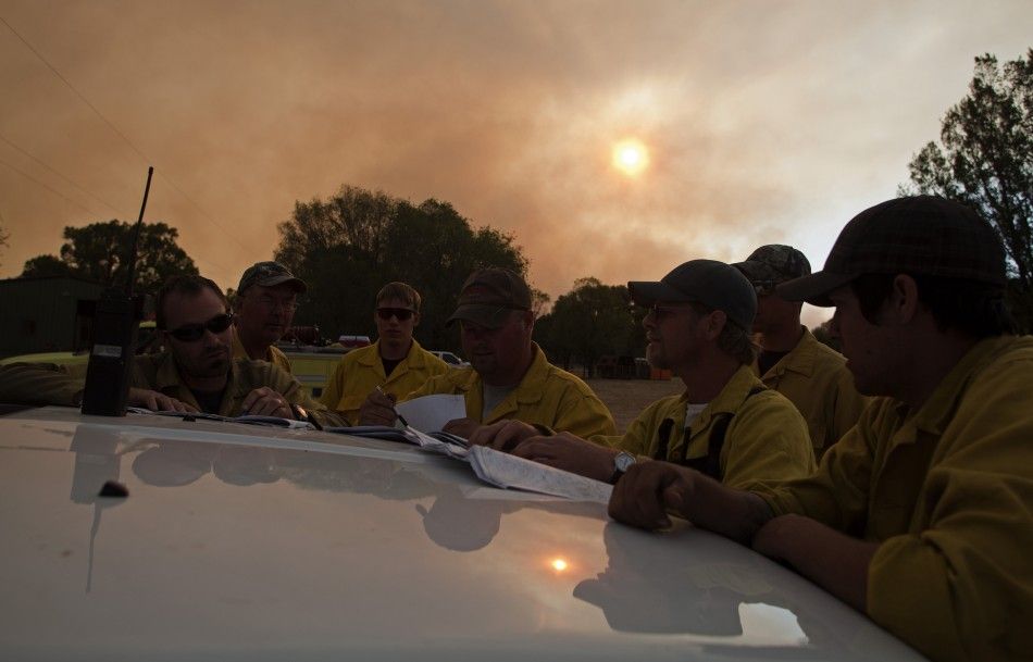 Wildland firefighters go over maps of the Wallow Wildfire as the sun sets in Luna, New Mexico