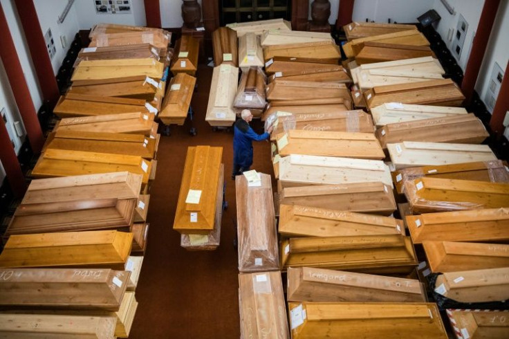 An employee moves coffins, some marked with "infection risk" as others have "corona" scrawled in chalk, in the mourning hall of the crematorium in Meissen, eastern Germany