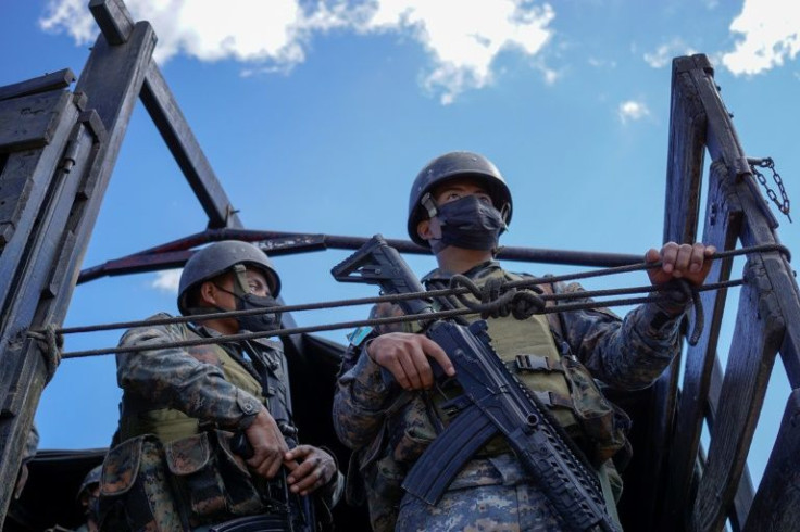 Soldiers stand guard close to a dirt road leading up to the village of Chiquix in western Guatemala where 13 people were killed in a massacre