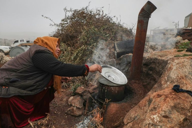 Umm Mohammad cooks outside at a makeshift displacement camp in Syria's Idlib province
