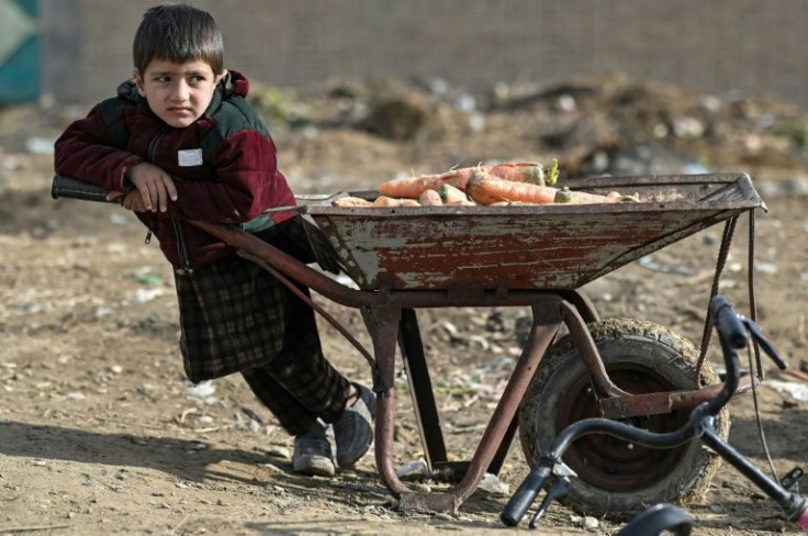 A child rests next to a wheelbarrow filled with carrots in Balkh, northwest of Mazar-i-Sharif on December 22, 2021, at a time when Afghanistan is facing economic collapse