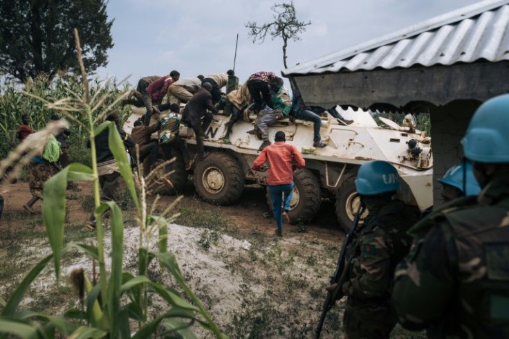 Red Cross volunteers climb onto a UN armoured vehicle after coming under attack