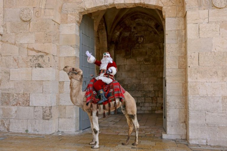 A Palestinian man dressed as Santa Claus gestures as he rides a camel in Jerusalem's Old City