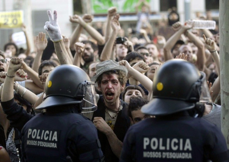 Riot police stands in front of protesters as they gather outside the Catalonia Regional Parliament before the budget debate in Barcelona