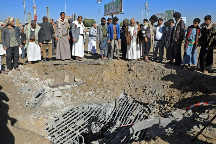 Yemenis inspect a crater following a reported air strike by the Saudi-led coalition targeting a road at Al-Sabeen square in the Huthi rebel-held capital Sanaa, on December 23, 2021