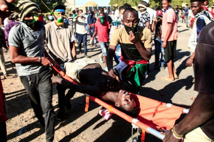 Sudanese youths carry away a fellow protester from the scene of confrontations with security forces during the demonstrations in Khartoum