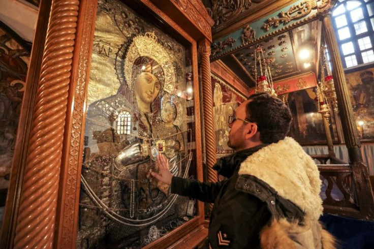 Milad Ayyad, a Palestinian Greek Orthodox Christian from Gaza, touches the icon of the Virgin and Child for a blessing at the Greek Basilica at the Church of the Nativity, where tradition says Jesus was born in Bethlehem, the occupied West Bank